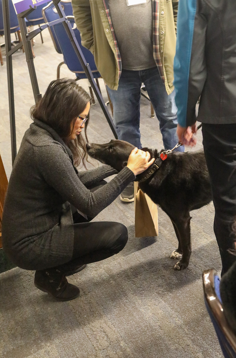 Women kneels down to pet a dog brought to the Tech Showcase and Social by Therapaws of Michigan. Photograph by Joel Iverson, ITS Marketing and Communications